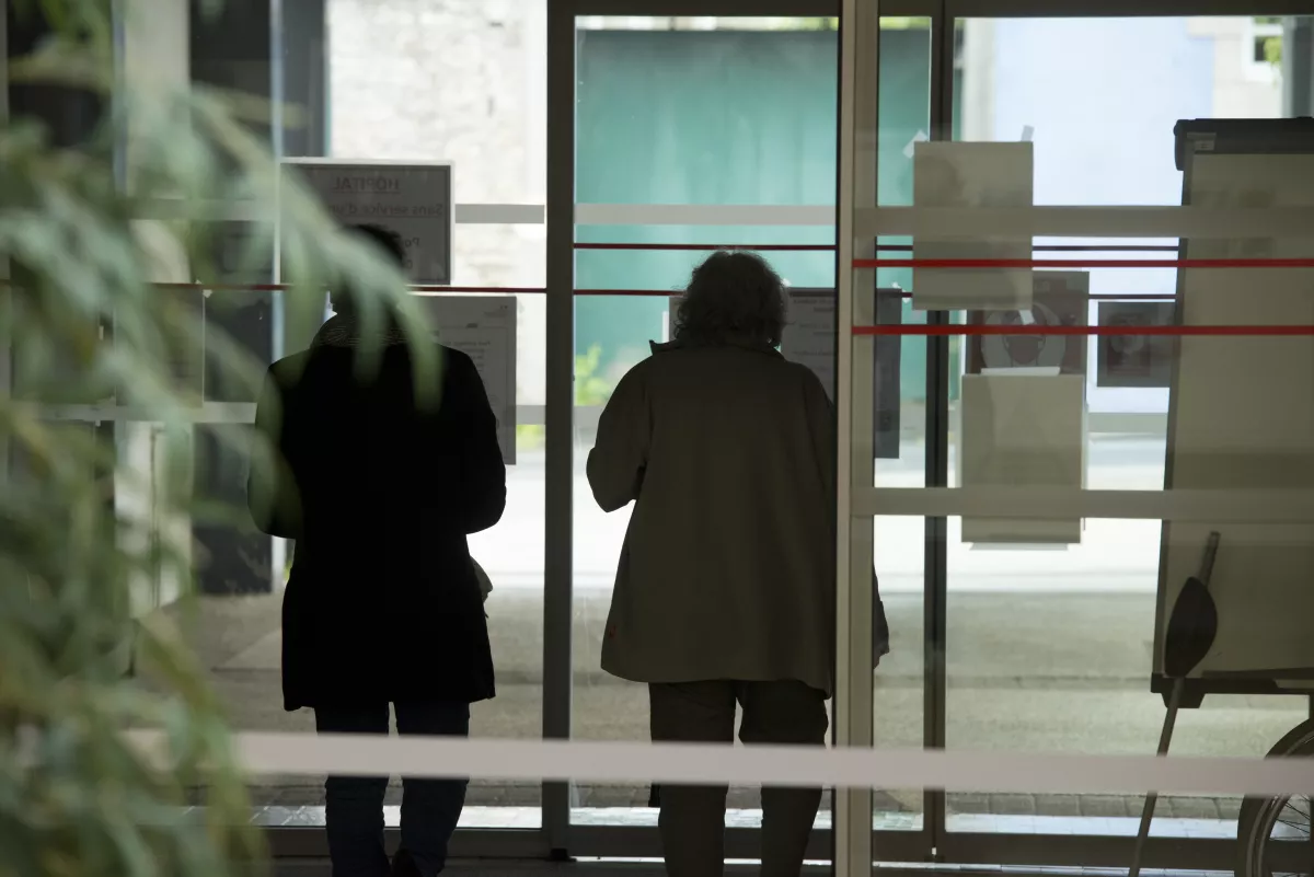 personnes de dos entrant dans l'hôpital la nuit